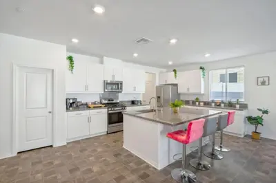 a kitchen with white cabinets and a counter with pink chairs at Entire Private Home with 4 Bedrooms 2 Bathrooms, Mountain Edge, New House, Ranch, Gated Yard, Available Now in Menifee