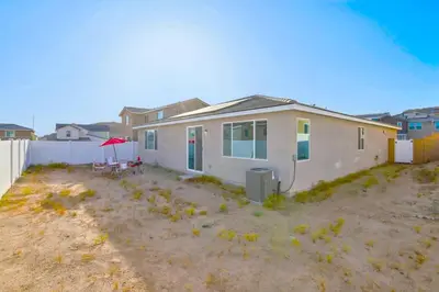 a white house with a red umbrella in a yard at Entire Private Home with 4 Bedrooms 2 Bathrooms, Mountain Edge, New House, Ranch, Gated Yard, Available Now in Menifee