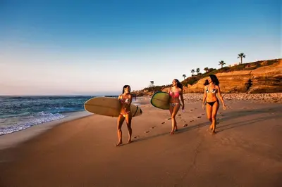 three women walking on the beach with their surfboards at Pipeline in San Diego