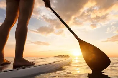 a person standing on a paddle board in the water at Pipeline in San Diego