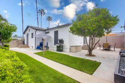 a white house with a tree in a yard at Pipeline in San Diego