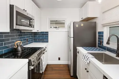 a kitchen with white cabinets and blue tiles at Surf Cottage 1 in San Diego