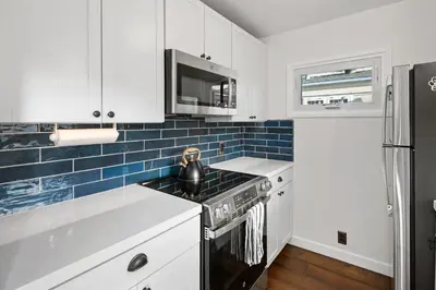 a kitchen with white cabinets and blue tiles at Surf Cottage 1 in San Diego