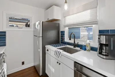 a kitchen with white cabinets and a stainless steel refrigerator at Surf Cottage 1 in San Diego