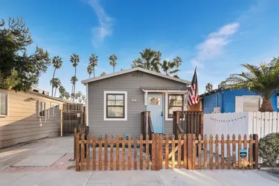 a gray house with a fence in front of it at Surf Cottage 1 in San Diego