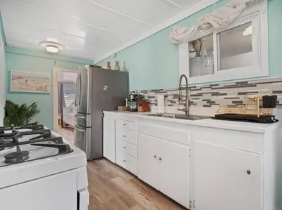 a kitchen with white cabinets and a stainless steel refrigerator at Comfy Cottage Near the Beach in San Diego