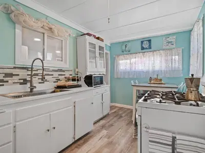 a kitchen with white cabinets and a sink and a stove at Comfy Cottage Near the Beach in San Diego