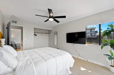 a white bedroom with a bed and a flat screen tv at Stylish & Bright 5 Star Location Ocean View Queen Beds in San Diego