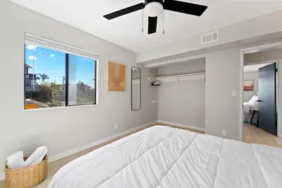 a bedroom with a white bed and a ceiling fan at Stylish & Bright 5 Star Location Ocean View Queen Beds in San Diego