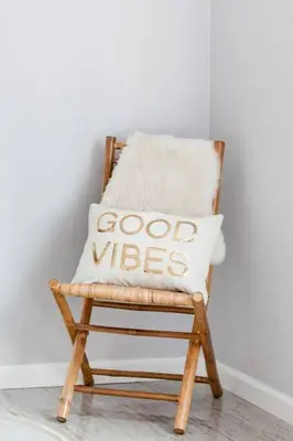 a wooden chair with a pillow that says good vibes at Creative Haven Chic 3-Bedroom with Artistic Touches in San Diego