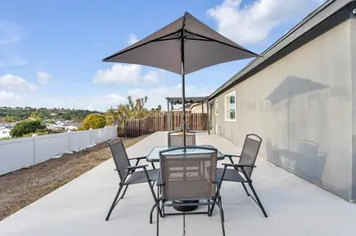 a table with chairs and an umbrella on a patio at Hilltop Home Hot Tub BBQ Game Room Self Check-In in Poway