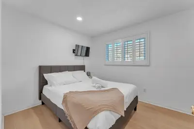 a bedroom with a bed with white sheets and a window at Hilltop Home Hot Tub BBQ Game Room Self Check-In in Poway