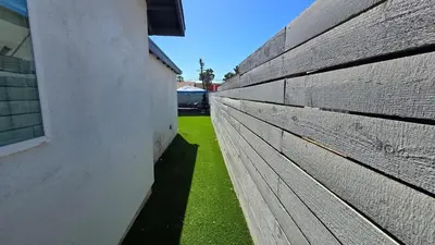 a wooden fence next to a building with green grass at Exotic home Sdstay-com in Spring Valley