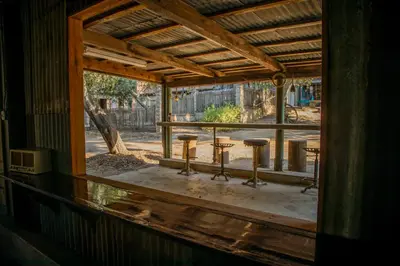 an outside window of a building with stools on a porch at Historic Farmhouse on 5 Peaceful Acres with Ancient Oaks & Creek above Temecula in Temecula