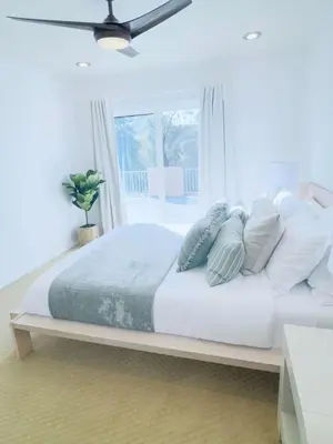 a bedroom with a white bed with pillows and a window at Del Mar Coastal Haven in San Diego