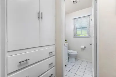 a white bathroom with a toilet and a window at Bayfront Apartment Steps to the Sand - Ultimate Coastal Living in San Diego