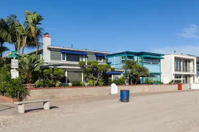 a building on the beach with a bench in front of it at Bayfront Apartment Steps to the Sand - Ultimate Coastal Living in San Diego