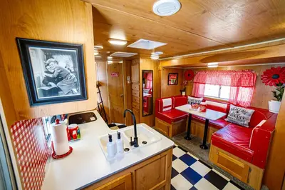 a kitchen with a sink and red chairs in a train at Darling Daisy Retro RV Adventure in El Cajon