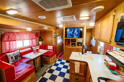 a kitchen with red chairs and a sink in a trailer at Darling Daisy Retro RV Adventure in El Cajon