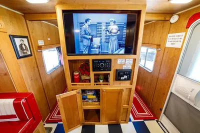 a room with a tv in a train car at Darling Daisy Retro RV Adventure in El Cajon