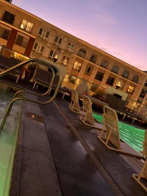 a hotel with chairs and a swimming pool in front of a building at Private stay SD in San Diego