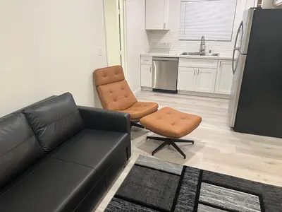 a living room with a couch and a chair and a kitchen at Modern and charming 1 bed first floor apartment in La Mesa