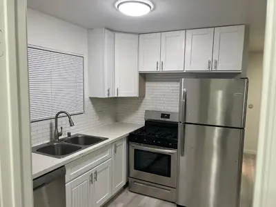 a kitchen with white cabinets and a stainless steel refrigerator at Modern and charming 1 bed first floor apartment in La Mesa
