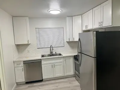 a kitchen with white cabinets and a stainless steel refrigerator at Modern and charming 1 bed first floor apartment in La Mesa