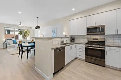 a kitchen with white cabinets and a dining room at Salt Haven in Oceanside
