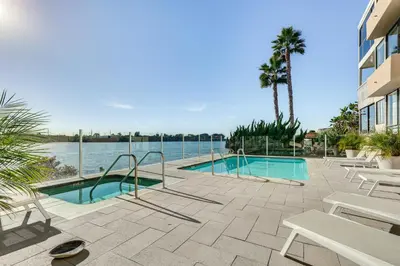 a swimming pool with tables and chairs next to the water at Waterfront Condo with Dock Access in Carlsbad! in Carlsbad