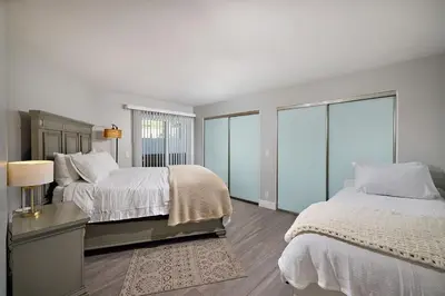a white bedroom with two beds and a window at Ocean Front Walk in San Diego