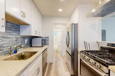 a kitchen with white cabinets and a stainless steel refrigerator at Cozy Couples Escape! Walk to San Clemente Pier in San Clemente