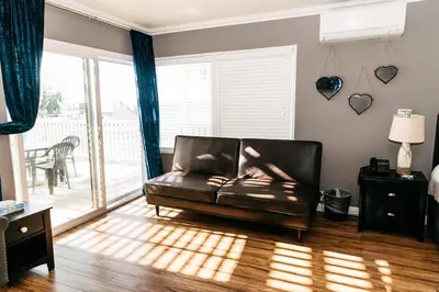 a leather couch in a living room with a sliding glass door at Laguna Cove Hotel in Laguna Beach