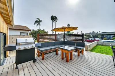 a patio with a couch and a grill and an umbrella at House Kitsune - Steps to Beach in Oceanside