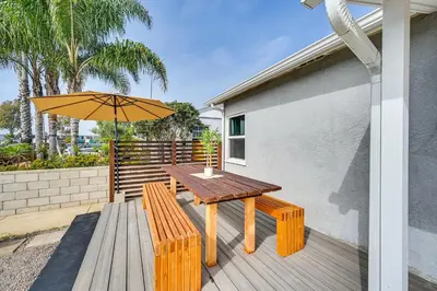 a wooden table and benches with an umbrella on a deck at House Kitsune - Steps to Beach in Oceanside