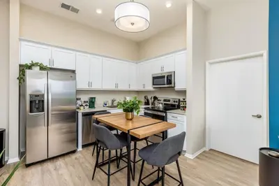 a kitchen with white cabinets and a wooden table and chairs at Artistic FastWiFi Parking Pets in San Diego