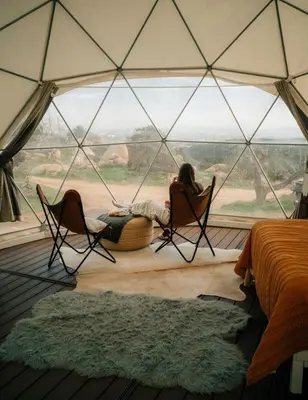 a woman sitting in chairs in a tent looking out the window at A Cozy Fireside Glamping Escape with Ridge Views in Fallbrook