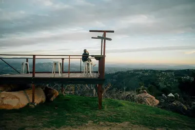 a person sitting on a cross on top of a mountain at A Cozy Fireside Glamping Escape with Ridge Views in Fallbrook