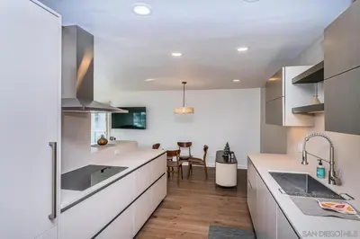 a kitchen with white cabinets and a dining room at Top Floor Oceanfront Condo in San Diego