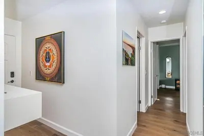 a hallway with white walls and a painting on a wall at Top Floor Oceanfront Condo in San Diego