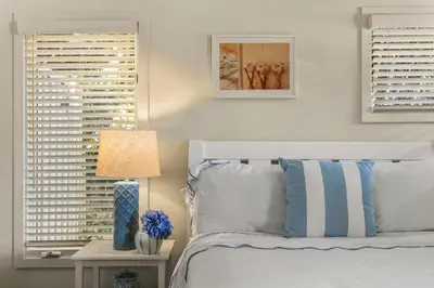 a bedroom with a bed and two windows with shutters at Classic Cottage in the Heart of La Jolla Shores in San Diego