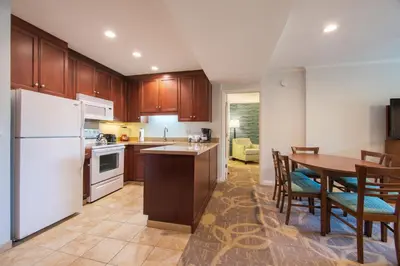 a kitchen with a table and a white refrigerator at Winners Circle Resort in Solana Beach