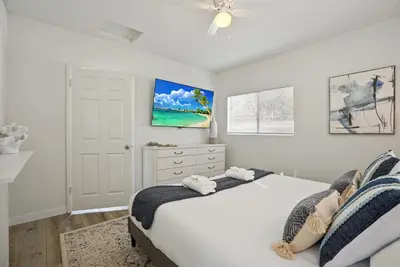 a white bedroom with a bed and a ceiling fan at Draper Bungalow By CoastVH - Charming 1940 in San Diego
