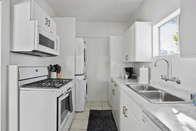 a white kitchen with a sink and a stove at Draper Bungalow By CoastVH - Charming 1940 in San Diego