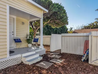 a porch with two blue chairs and a fence at Draper Bungalow By CoastVH - Charming 1940 in San Diego