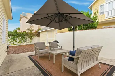a patio with three chairs and an umbrella at Draper Bungalow By CoastVH - Charming 1940 in San Diego