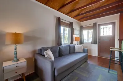 a living room with a blue couch and windows at Surf Cottage 2 in San Diego
