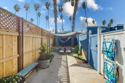 a patio with a fence and a bench and palm trees at Surf Cottage 2 in San Diego