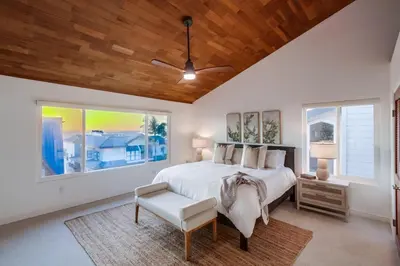 a bedroom with a bed and a chair and windows at Cardiff View in Cardiff-by-the-Sea