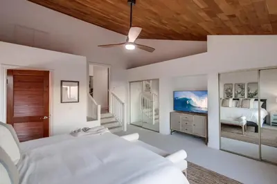 a white bedroom with a bed and a ceiling fan at Cardiff View in Cardiff-by-the-Sea